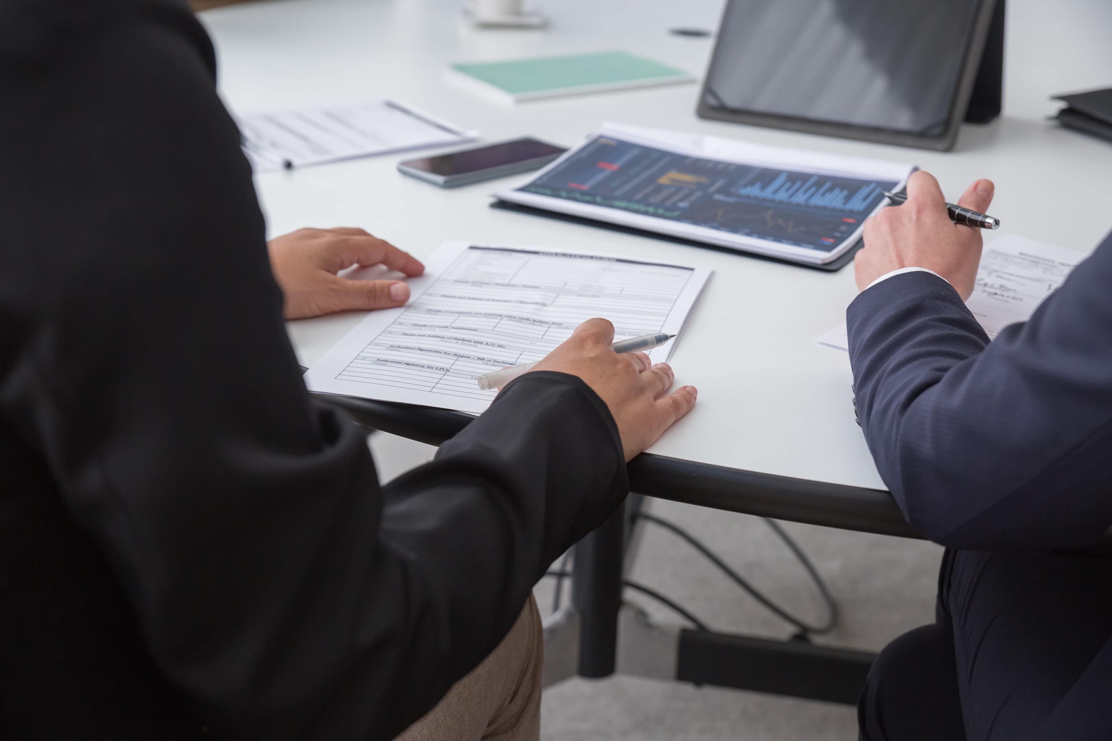 2 people infront of a desk looking at graphs